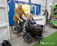 People demonstrating bicycle with compartment for sitting in the front