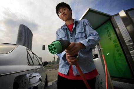 Person holding electric charger by car