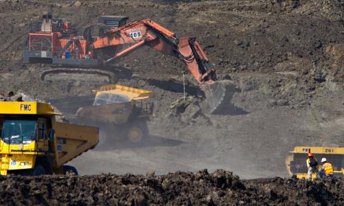 Dump trucks and cranes carrying and extracting coal from a coal work site.